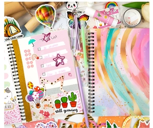 Flat lay of DIY stationery set with spiral notebooks, artistic stickers, and colorful pens