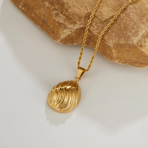 Gold shell pendant necklace with twisted rope chain on minimalist background