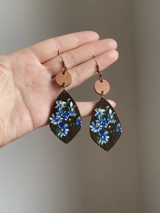 Detail of vintage teardrop wooden earrings with hand-painted blue daisies and bronze hooks
