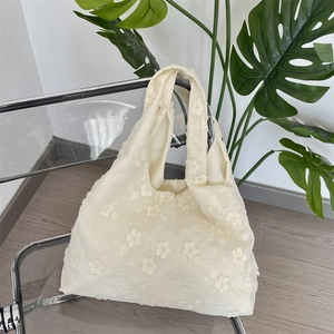 Detail of floral embroidery on cream white canvas tote bag in a minimalist home setting