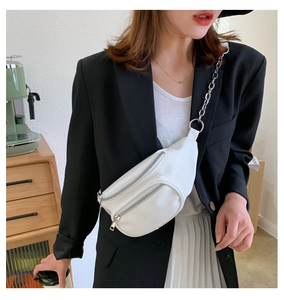 Detail of white faux leather chest bag with silver chain strap and double zipper pockets