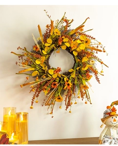 Vue détaillée d'une couronne d'automne avec fleurs jaunes et branches sur un mur blanc