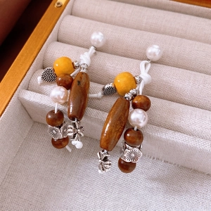 Ethnic vintage silver needle earrings with wood beads and floral charms in a beige box