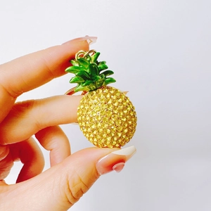 Detailed view of handmade pineapple keychain with yellow rhinestones and green enamel finish