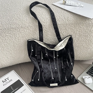 Detail of black velvet tote bag featuring pearl bead embroidery and white lining detail