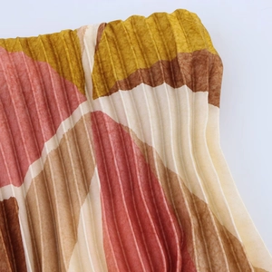 Gros plan sur un tissu plissé avec motif géométrique tons rouge-brun et jaune