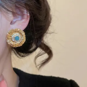 Vintage gold flower stud earrings with blue gemstone and zircon inlay on model