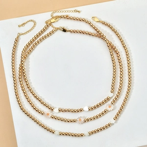 Three-piece set of gold beaded necklaces with white daisy and heart charms for women