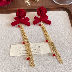 Detail of red flocked rose earrings with golden tassels and translucent beads