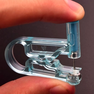 Detailed close-up of a blue disposable ear piercing gun being operated by hand