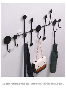 Minimalist black metal wall hook rack holding a bag and umbrella on a clean wall