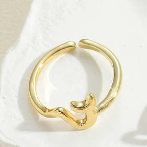 Detailed close-up of golden abstract wave ring with polished finish on stone surface