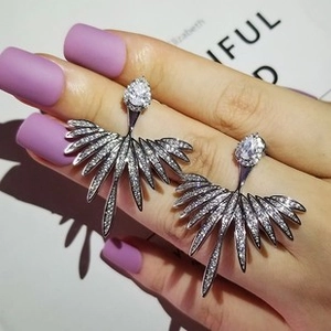 Detailed view of silver teardrop stud earrings with leaf-shaped zirconia on hand model
