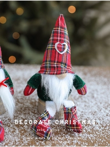 Detail of Christmas gnome plush with red plaid hat and white heart on a snowy background