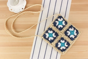 Détail de patchwork floral au crochet sur un sac bandoulière en paille avec bandoulière tressée