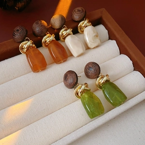 Detailed shot of vintage wood and resin geometric drop earrings in amber, cream, and green