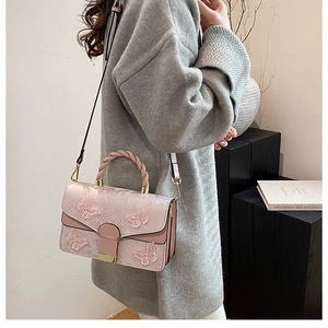 Détail du sac papillon brodé rose avec poignée tressée et finitions métalliques