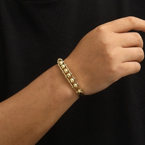 Modern gold beaded orbit bracelet on model wrist with elegant black clothing background