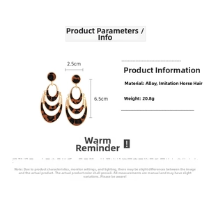Close-up of triple-layered leopard print oval drop earrings with golden metal frames