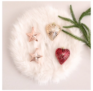 Close-up of metallic heart and star ornaments on white faux fur with pine needle accents