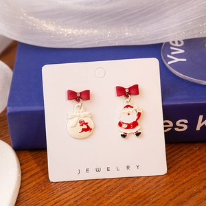 Detail of asymmetrical Christmas earrings featuring Santa and reindeer on white card