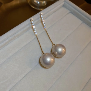 Detailed close-up of pearl tassel earrings with shimmering crystals on a velvet display