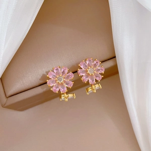 Macro shot of pink floral stud earrings with pear-cut cubic zirconia in gold setting