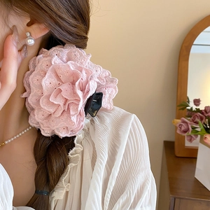 Détail d'une pince à cheveux en dentelle rose en forme de rose portée par un mannequin