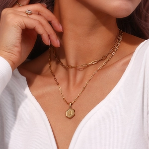 Detail of gold double-layered paperclip necklace with hexagonal letter J pendant