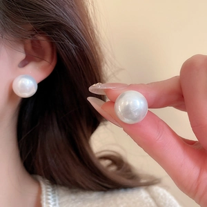 Detailed close-up of large round white pearl earrings showing smooth texture and high luster