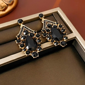 Macro shot of gold-plated V-shaped drop earrings with inlaid black gemstone and crystals