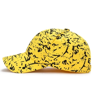 Yellow cotton baseball cap featuring black graffiti paint splatter and curved brim