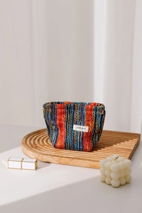 Detailed macro view of bohemian knit makeup bag featuring colorful stripes and floral zipper