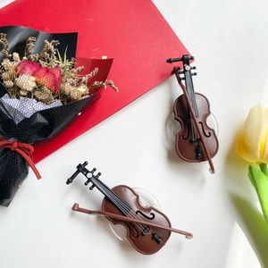 Detail view of miniature brown violin phone stands with matching bows and floral decor