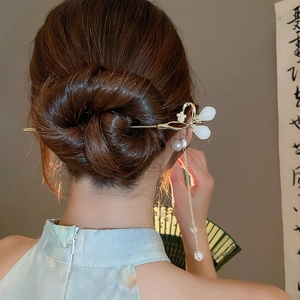 Vue détaillée d'une épingle à cheveux chinoise dorée avec pompon en perles sur modèle