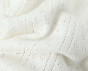 Détail rapproché d'un tissu en maille blanche avec motifs ajourés et textures côtelées fins