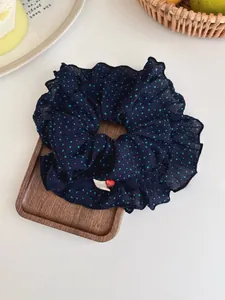 Detail of navy polka dot scrunchie with heart label on a decorative wooden tray