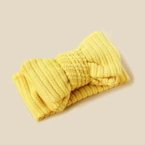 Detail of yellow knitted baby headband showing texture and a large double-layer bow