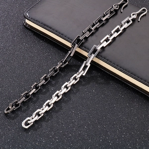 Detailed close-up of geometric silver and gun black chain links on a dark leather texture