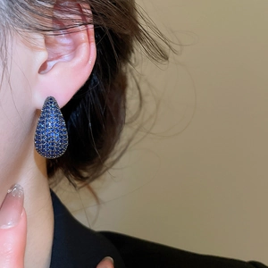 Close-up of teardrop stud earring with navy blue crystals on model for a chic look