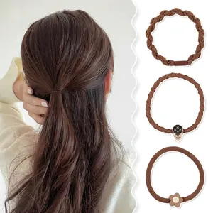 Detailed set of three brown elastic hair ties with floral and vintage metallic charms