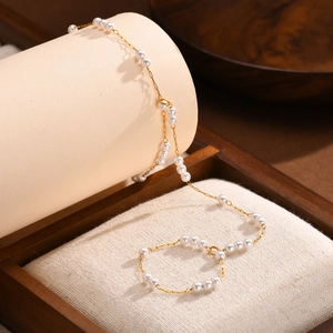 Macro shot of double-layer gold chain with white pearls and lobster clasp detail