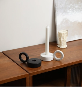 Close-up of modern ceramic candle holders with ring handles on a wooden table