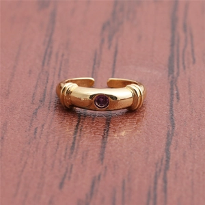 Close-up of golden adjustable ring featuring a round purple zircon on a wooden background