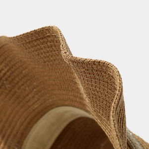 Detailed macro view of woven straw hat texture with wavy brim and inner sweatband
