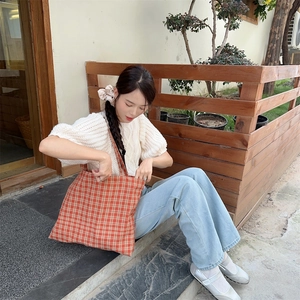 Outdoor lifestyle shot of a red checkered canvas tote bag showing its large capacity