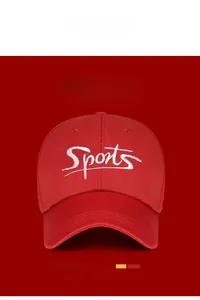 Detail of red baseball cap featuring white Sports embroidery and curved brim design