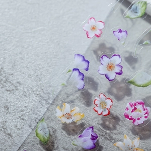 Floral 3D nail art stickers featuring colorful cherry blossoms on a stone background