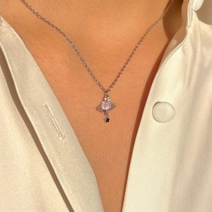 Close-up of pink gem Saturn pendant with star charm on silver chain worn by model