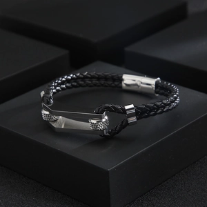 Macro detail of men's braided leather bracelet featuring a U-shaped silver metal clasp